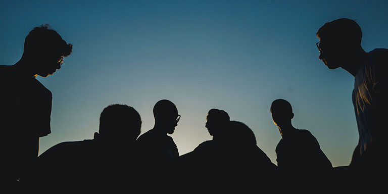 silhouette of a group of people in front of a blue night sky