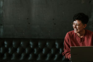 smiling woman sitting on couch with laptop